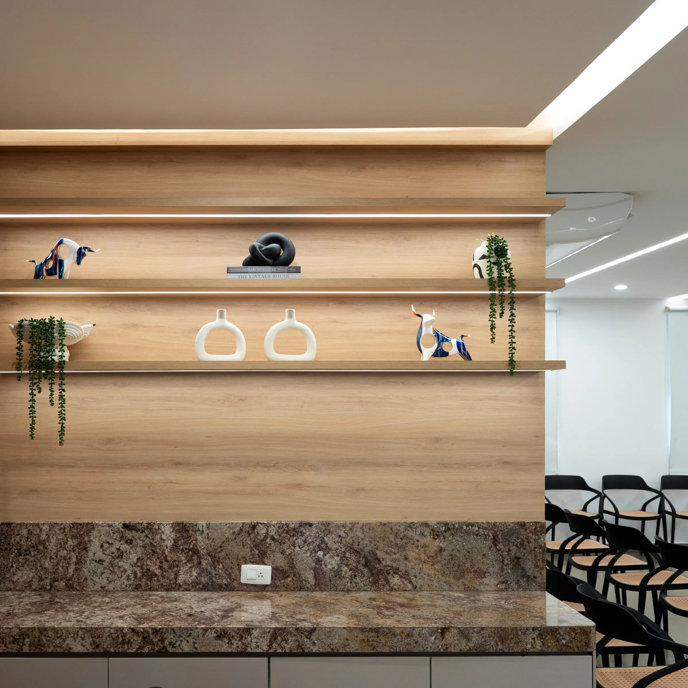 Repisas de madera con decoración junto al mesón de mármol del auditorio